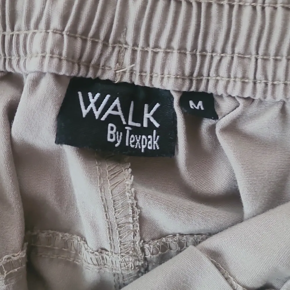Säljer ett par beige cargobyxor från Walk by Texpak. Byxorna har flera praktiska fickor och en elastisk midja för extra komfort. Perfekta för en avslappnad stil. Har lite slitningar där olika metallknappar rostat men inget man lägger så stort märke till.!. Farkut & Housut.