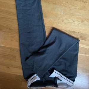 Grå byxor med vita detaljer kostymbyxor - Snygga grå byxor med vita och svarta ränder längs sidorna. Perfekta för en avslappnad stil. Byxorna är bekväma.