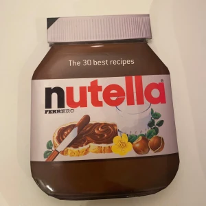 Nutella: The 30 Best Recipes - Upptäck de 30 bästa recepten med Nutella i denna unika kokbok formad som en Nutella-burk. Perfekt för alla Nutella-älskare som vill utforska nya och spännande sätt att använda den populära hasselnötskrämen i sina bakverk och desserter.