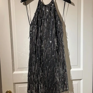Mini klänning med paljetter - Snygg svart glittrig halterneck klänning från pull&bear med paljetter och en kort design. Perfekt för en kväll ute eller nu inför nyår! Säljer då den aldrig kommit till användning. Den är helt oanvänd och lappen är kvar på✨🩷Nypris:349kr