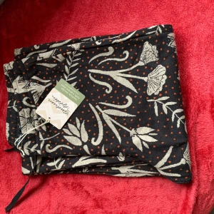 Svart och beige byxa med blommönster - Snygga byxor i svart med beige blommönster och små orange prickar. Perfekta för en unik stil. Byxorna har en lös passform och är tillverkade i ett mjukt material.