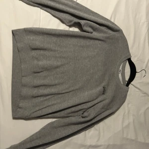 Grå tröja från Helly Hansen - Säljer en stilren grå tröja från Helly Hansen. Tröjan har en enkel design med långa ärmar och rund halsringning. Perfekt för en avslappnad look.