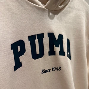 Ny hoodie från Puma - Säljer en helt ny hoodie från Puma med grön text 'PUMA Since 1948' på bröstet. Tröjan har en hoodie och ribbade muddar i grön vid ärmslut.