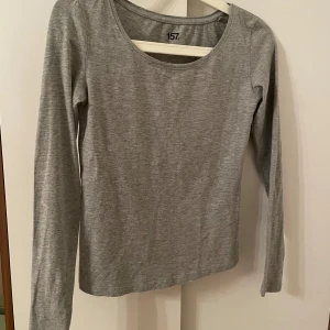 Grå långärmad tröja från 157 - Säljer en enkel och stilren grå långärmad tröja från Lager  157. Perfekt för vardagsbruk med sin mjuka och bekväma passform. Tröjan har en rund halsringning och är tillverkad i ett lätt material. Sydd  under ena armhålan ( se bild ).