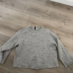 Grå stickad tröja från H&M Divided - Säljer en mysig grå stickad tröja från H&M Divided. Tröjan har en klassisk design med långa ärmar och ribbstickad krage. Storlek L, för en overzise känsla.
