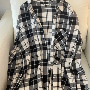 Svartvit rutig skjorta - Säljer en snygg svartvit rutig skjorta i storlek 38. Den har en klassisk krage och knappar framtill. Perfekt för både vardag och fest! Skjortan är i bra skick och passar till många olika stilar. 🖤🤍