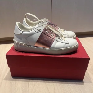 Valentino Open sneakers rosa vita - Säljer mina favorit skor då jag tyvärr växt igen dom, behöver en större storlek.  Valentino Open sneakers i vitt skinn med en cool rosa metallic detalj. Skorna har snörning och är i mycket bra skick. Perfekta för både vardag och festliga tillfällen!