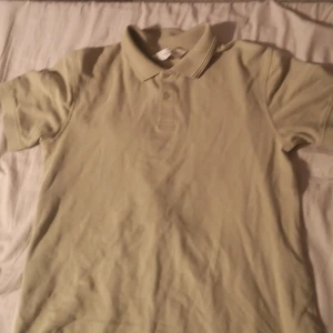 Beige pikétröja från H&M - Säljer en klassisk beige pikétröja från H&M i storlek EUR 158/164. Perfekt för en avslappnad stil, med korta ärmar och knappar framtill. Tröjan är i bra skick och passar både till vardags och lite finare tillfällen. Skön och enkel att matcha med det mesta! 🌟