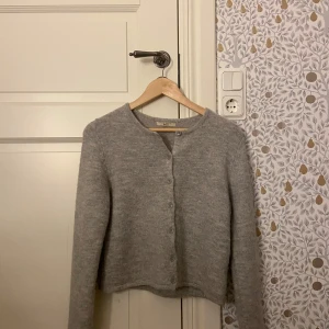 Stickad kofta - Stickad kofta från Gina tricot. I mycket bra skick och väldigt sparsamt använd.  Ljusare grå i verkligheten, det är ljuset som får den att se något mörkare ut🥰 relativt liten i storleken, snarare som en xs 