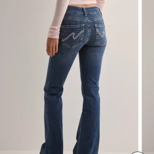 Blå bootcut jeans - Snygga blå bootcut jeans i nytt skick. De har  sömmar på bakfickorna. Perfekta för både vardag och fest! Passformen är tight upptill och blir vidare nedtill för en skön och trendig look. Beställde för 699kr+frakt aldrig använda då de inte passade. SMÅ I STORLEKEN lapp är kvar