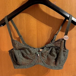 Grå spetsbehå från Gerard Pasquier - Elegant grå spetsbehå från Gerard Pasquier med dekorativ rosett och hängsmycke framtill. Behån har justerbara axelband och en vacker spetsdesign som ger en lyxig känsla.