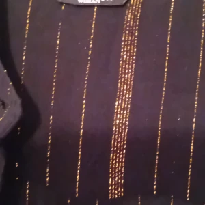 Svart klänning med guldglitter - Snygg svart långklänning med glittriga guldlinjer. Perfekt för festliga tillfällen! Klänningen har långa ärmar och en elegant passform som ger en lyxig känsla. Perfekt för nyår eller andra speciella tillfällen.