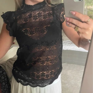 Svart spetsblus! - Säljer en svart spetsblus. Blusen har korta ärmar med volangdetaljer, pris kan diskuteras 🌟