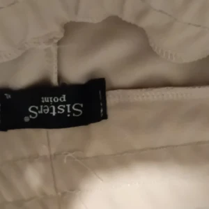 Beige byxor från Sisters Point - Snygga beige byxor från Sisters Point i storlek XL. De har en stilren design med en praktisk ficka på sidan. Perfekta för en avslappnad men ändå chic look. Passar bra till både vardag och fest!