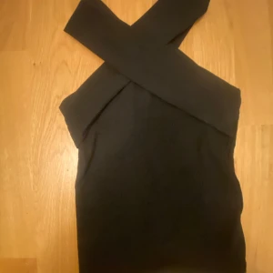 Linne - Ett linne med korsande band på både fram och baksida. Linnet är ribbat,svart och funkar både att klä upp och ner. Det är från Gina och i xxs men funkar bra till mig som är xs. Det är i väldigt bra skick då jag bara använt det en gång när jag hade köpt det. Kommer alltså inte till användning. 