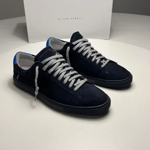 Blåa sneakers Oliver Cabell - Snygga blåa sneakers från Oliver Cabell i mocka med grå snörning. Perfekta för en avslappnad och trendig look. Skorna har aldrig använts utanför dörren, därmed är skicket 10/10. Allt original medföljer. OBS kvitto finns ej!