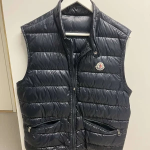 Moncler Gui Väst - Tja säljer en Moncler Gui väst i färgen Navy, strl 3 (motsvarar en större M). Västen är i  ett sparsamt skick. Fraktar gärna, finns och hämta i Bollebygd annars!    Hör av er vid frågor.   