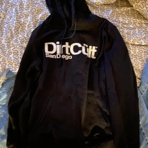 Svart hoodie från DirtCult - Säljer en svart hoodie från DirtCult med tryck 'San Diego' på framsidan. Den är i bra skick och perfekt för både höst och vinter. Hoodien har en klassisk passform med en stor ficka framtill och justerbar huva. Perfekt för en avslappnad stil eller en dag ute med vänner. 🖤