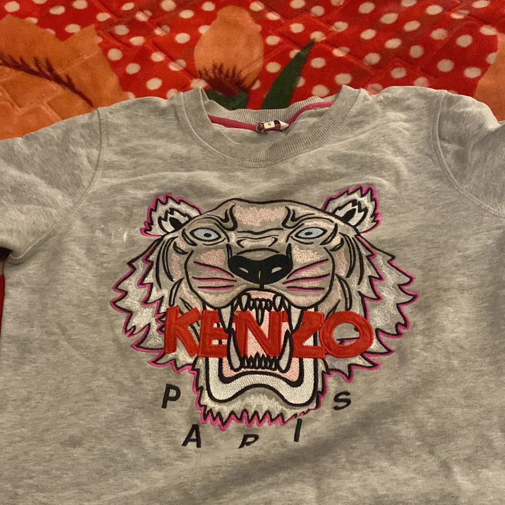 Säljer en grå sweatshirt från Kenzo med ett coolt tigertryck och texten 'Kenzo Paris' på framsidan. Tröjan är i bra skick och har långa ärmar. Perfekt för en avslappnad stil eller att bära till vardags. 🐯. Tröjor & Koftor.