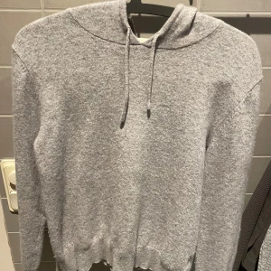 Cashmere - Säljer en supermysig grå hoodie i cashmere. Perfekt för kyliga dagar med sin bekväma passform och klassiska design. Den har en justerbar huva med snören och ribbade muddar vid ärmslut och nederkant. Passar både till vardags och för avslappnade stunder hemma.Är liten i storleken men passar bra som xs