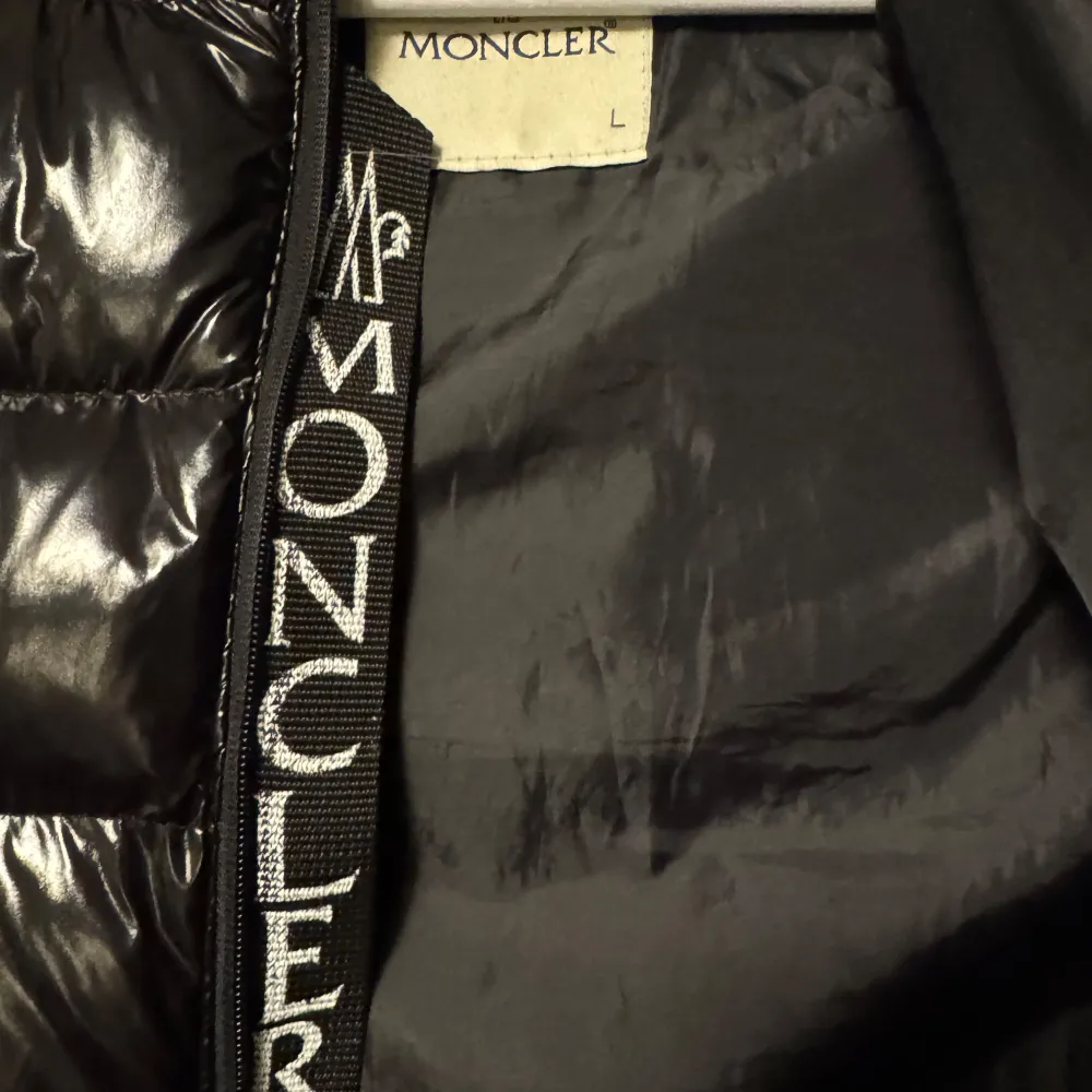 Säljer en snygg svart dunväst från Moncler i storlek L. Västen har en glansig finish och är quiltad med dragkedja framtill. Perfekt för höst och vinter, håller dig varm och stilren. Moncler-logga på bröstet och en cool serietidningsetikett på insidan. Passar både till vardags och fest! Västen har en ytterst liten effekt vid ena fickan som ni kan se på sista bilden, annars är den i toppen skick. Priset kan diskuteras😊. Jackor.