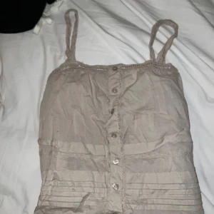 Beige linnetopp från JDY - Säljer en söt beige linnetopp från JDY med knappar framtill och spetsdetaljer längs kanterna. 