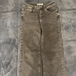 Grå jeansbyxor - Snygga grå jeansbyxor med en klassisk femficksdesign. Byxorna har en rak passform och är perfekta för en avslappnad stil. De har en knapp och dragkedja framtill.