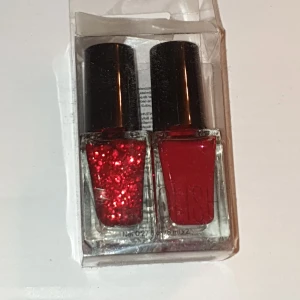 Rött nagellack set - Två nagellack. Oanvända. Ena lacket är rött med glitter, perfekt för festliga tillfällen eller såhär runt juletider. :) Det andra är ett klassiskt, basic rött lack typ..för en mer elegant look eller vid vardags. Båda har svarta lock och kommer i en genomskinlig plastförpackning 