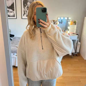 Beige fleece hoodie från H&M - Mysig beige hoodie från H&M i fleece med dragkedja och stor ficka framtill. Perfekt för kyliga dagar med sin varma och bekväma design. Den har en luva för extra värme och stil.