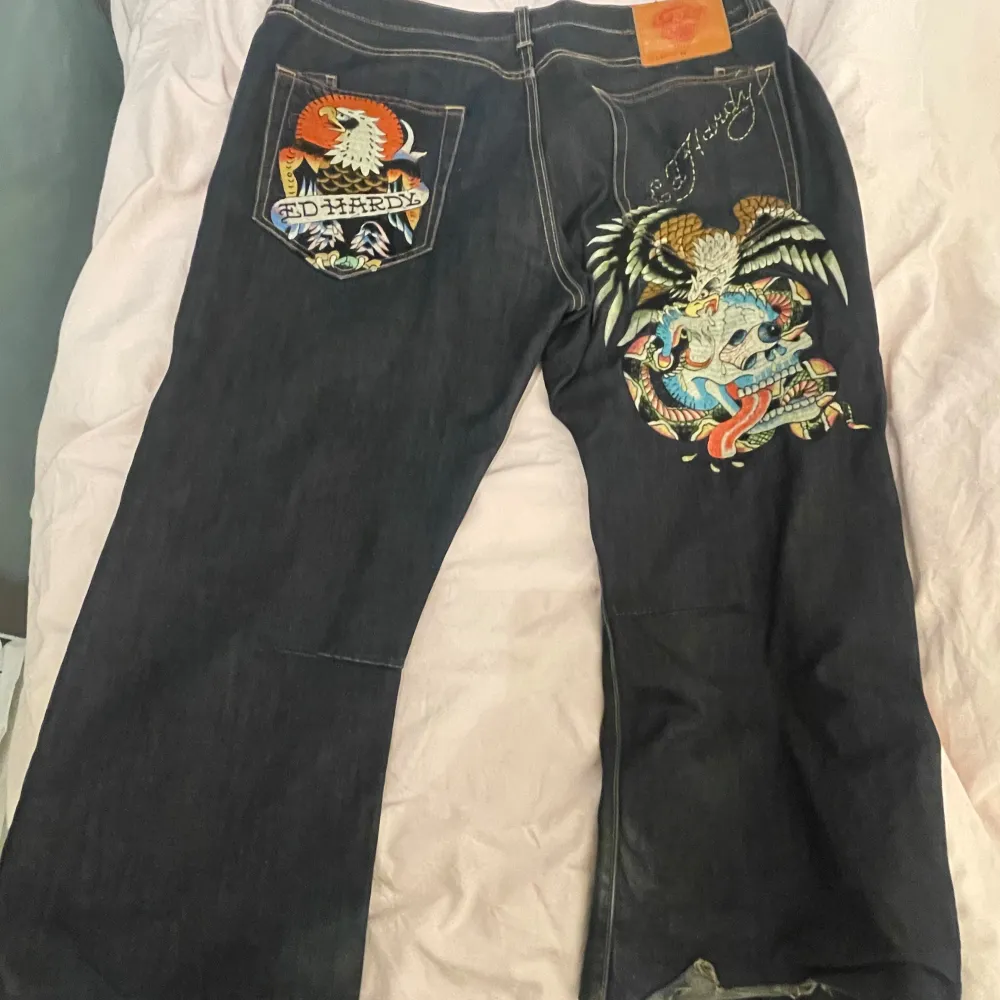 Säljer ett par ascoola baggy Ed Hardy jeans! Dem är eltejpade upp i benen (kan skicka bild) då dem är alldeles för långa för mig (165)❤️Har lite små fläckar/missfärgningar❤️. Jeans & Byxor.