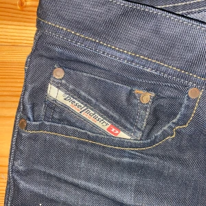 Mörkblå jeans från Diesel - Säljer ett par snygga mörkblå grå jeans från Diesel i bra skick. De har en klassisk femficksdesign med tydliga sömmar och en liten logga på myntfickan. Perfekta för både vardag och fest! 🕺w31 L34