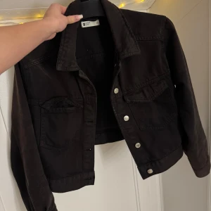 Svart jeansjacka från Gina Tricot - Säljer en snygg svart jeansjacka från Gina Tricot i storlek XS. Jackan har en klassisk design med knappar framtill och två bröstfickor. Perfekt för höst och vår, och ger en cool look till vilken outfit som helst. Den är lite solblekt men bara att lägga i ”svart färg” när man tvättar den så blir den som ny igen, vid frågor kontakta mig 🫶🏽