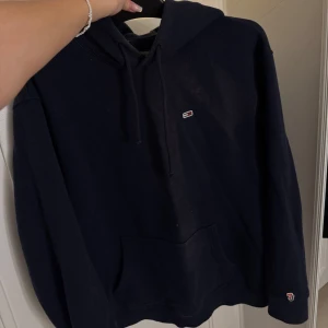 Hoodie Tommy Hilfiger - Säljer en klassisk hoodie från Tommy Hilfiger. Den har en liten logga på bröstet och en större på ärmen. Perfekt för höst och vinter, med en skön passform och känguruficka framtill. Huvan har dragsko för justering. Passar både till vardags och chillkvällar. 🖤Storlek M, pris 200:- vid frågor kontakta mig 🫶🏽