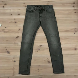 Grå jeans från Tommy Hilfiger - Snygga grå jeans från Tommy Hilfiger med en klassisk femficksdesign. De har en slim passform och är perfekta för en stilren look. Diskret logga på bakfickan ger en extra touch av stil.
