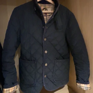 Burrbery jacka - Säljer en stilren mörkblå quiltad jacka från Burberry med klassiskt rutigt foder. Det är storlek M på den men passar väldigt bra till S. Hör av er vid eventuella frågor eller funderingar! 😊🤝🏽🤩