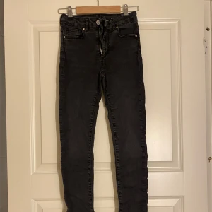 Svarta skinny jeans - Snygga svarta skinny jeans med hög midja och klassisk femficksdesign. Perfekta för en stilren look och passar till det mesta i garderoben.