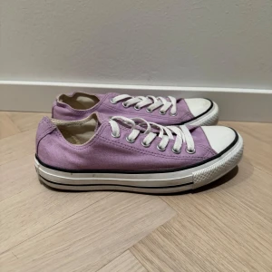 Lila Converse All Star sneakers - Säljer ett par klassiska lila Converse All Star sneakers med vit sula och snörning. Perfekta för en avslappnad stil.