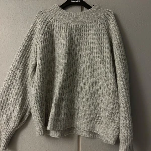 Grå stickad tröja från lager 157 - Mysig grå stickad tröja från lager 157 i storlek S. Perfekt för kyliga dagar med sin varma och bekväma passform. Tröjan har långa ärmar och en ribbad struktur som ger en stilren look. Passar både till vardags och mysiga hemmakvällar.