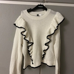 Vit stickad tröja med volangdetaljer - Säljer en superfin vit stickad tröja från h&m. Den har långa ärmar och snygga volangdetaljer med svart kant som ger en extra touch. Perfekt för både höst och vinter, och den är riktigt mysig att ha på sig. Passar perfekt till både jeans och kjol!