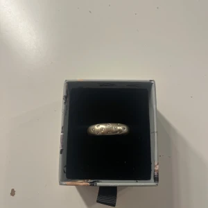 Silverfärgad ring med små stenar - Elegant silverfärgad ring med små stenar. Perfekt för att ge en stilren touch till din look. Ringen har en slät yta med små upphöjda stenar som ger en unik textur.