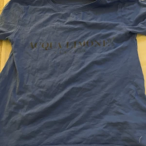 Blå t-shirt från Acqua Limone - Snygg blå t-shirt från Acqua Limone med tryck på både fram- och baksidan. Framsidan har märkesloggan i svart och baksidan pryds av en stor gul citronhalva. Perfekt för en avslappnad stil.