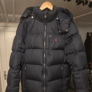 Svart dunjacka från Polo Ralph Lauren - Tjena! Jag skulle vilja byta denna Marinblåa Ralph Lauren jackan till en som är i storlek S då den är för stor för mig. Jackan är helt ny och är köpt på Boozt.se för drygt 5k (Och självklart finns etiketten kvar). Jag skulle även kunna sälja den men jag är helst intresserad i ett byte. Hojta till vid fler frågor🤝