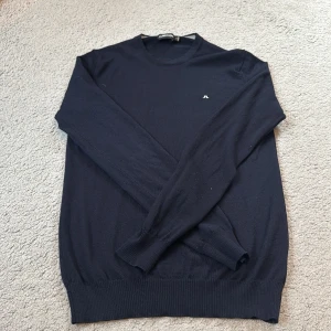 Marin blå tröja från J.Lindeberg - Säljer en stilren marin blå tröja från J.Lindeberg i mycket bra skick. Den är långärmad och har en liten logga på bröstet. Perfekt för både vardag och fest. Passar bra till höst och vinter. Nypris 1399.