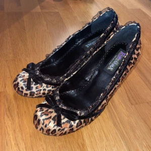 Leopardmönstrade ballerinaskor med klack - Snygga leopardmönstrade ballerinaskor med klack och rosett. Skorna har en spetsig tå och dekorativa volanger längs kanten. Perfekta för att ge en fab touch till din outfit! Originalpris: 623 kr