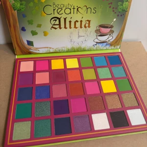 Ögonskuggspalett Alicia från Beauty Creations - Färgglad ögonskuggspalett med 35 nyanser från Beauty Creations. Paletten Alicia erbjuder en mix av matta och skimrande färger, inklusive rosa, blå, grön, gul och brun. Perfekt för kreativa och livfulla sminkningar.
