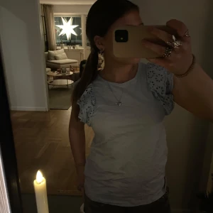 Ljusblå topp med spetsdetaljer - Säljer en söt ljusblå topp med spetsdetaljer på axlarna. Toppen har korta ärmar och en rund halsringning. 💘 endast använd 2 ggr då den är lite för liten på mig 🤍