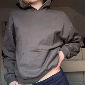 Grå hoodie - Säljer en grå hoodie med en klassisk design. Den har en stor ficka framme och en huva. Använd få antal gånger och är i väldigt på skick.
