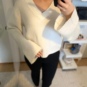 Vit stickad tröja med v-ringning - Säljer en mysig vit stickad tröja med v-ringning och långa ärmar. Tröjan har en lös passform och kan bäras offshoulder för en avslappnad look. Perfekt för kyliga dagar!