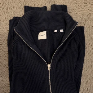 Mörkblå ribbad tröja från Jack & Jones - Säljer en stilren mörkblå ribbad tröja från Jack & Jones med dragkedja. Den är i storlek XL och passar bra till både vardag och avslappnade tillfällen. Väldigt fint skick☺️Vid smidig affär kan pris diskuteras☝️