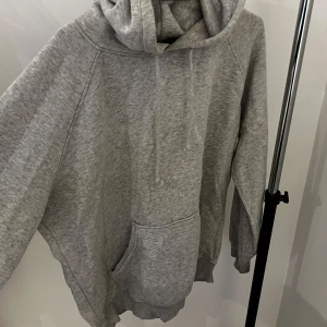 Grå hoodie från Bik Bok - Säljer en bekväm grå hoodie från Bik Bok i storlek M. Den har en klassisk design med en stor ficka framtill och justerbar huva. Perfekt för en avslappnad stil.